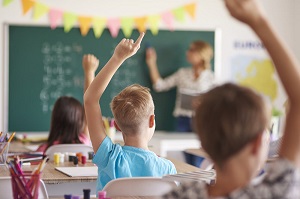 Kid putting his hand up in classroom